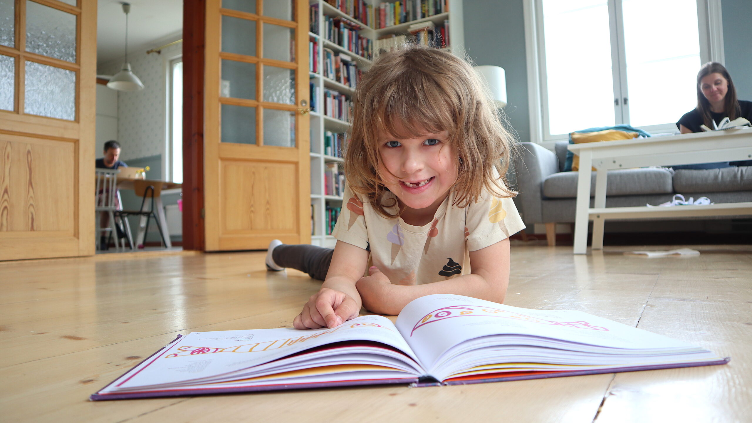 Bild av flicka som ligger på golvet med en bok framför sig.