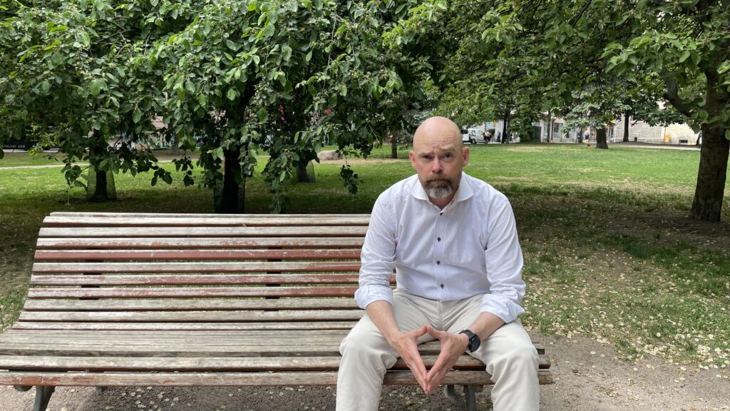 Foto av man som sitter på en bänk i en park.