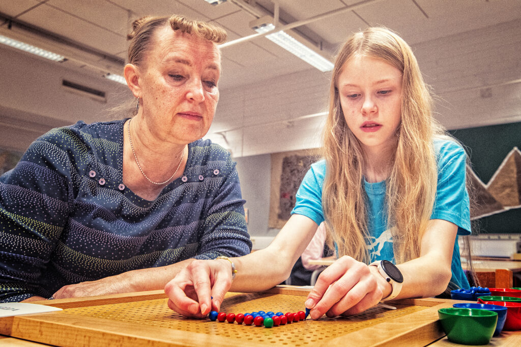 Lärare som sitter bredvid en elev som räknar med räknepärlor.