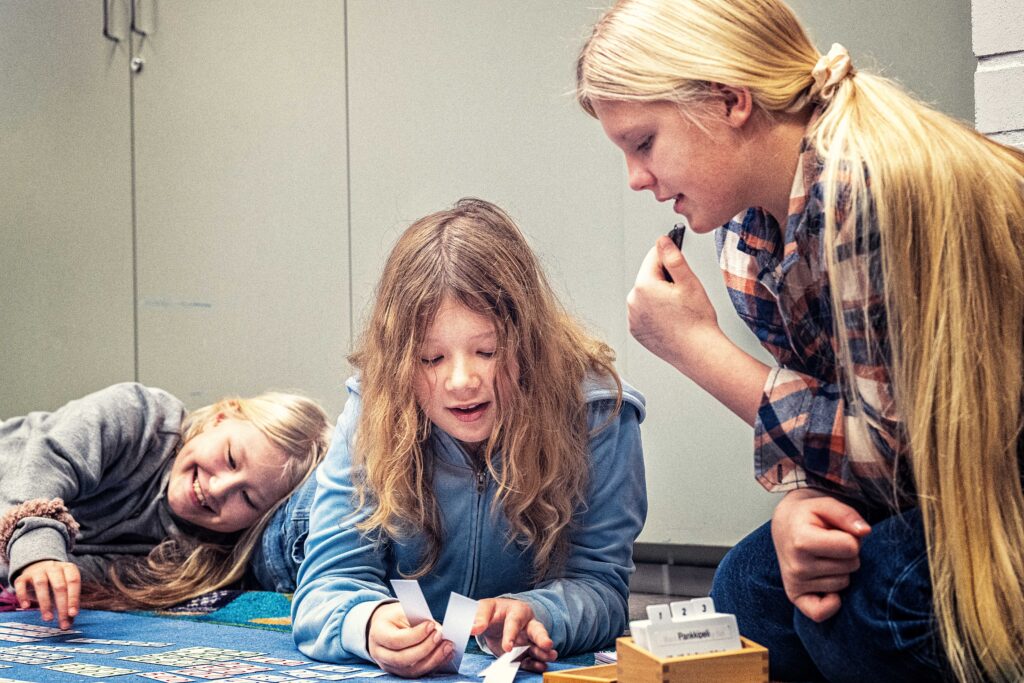Tre elever som sitter på golvet och spelar ett spel. 