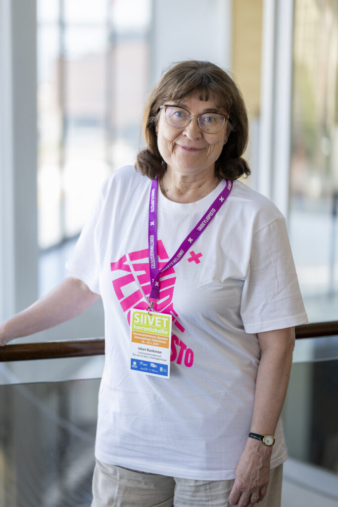 Bild av mörkhårig kvinna med glasögon, som står lutad mot ett trappräcke.